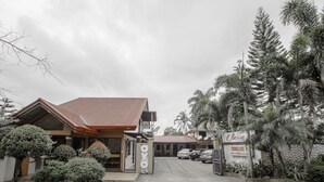 A hotel entrance with a covered parking area, a signboard, and surrounding tropical vegetation. - OYO 741 Sierra Travellers Inns (Tagaytay)