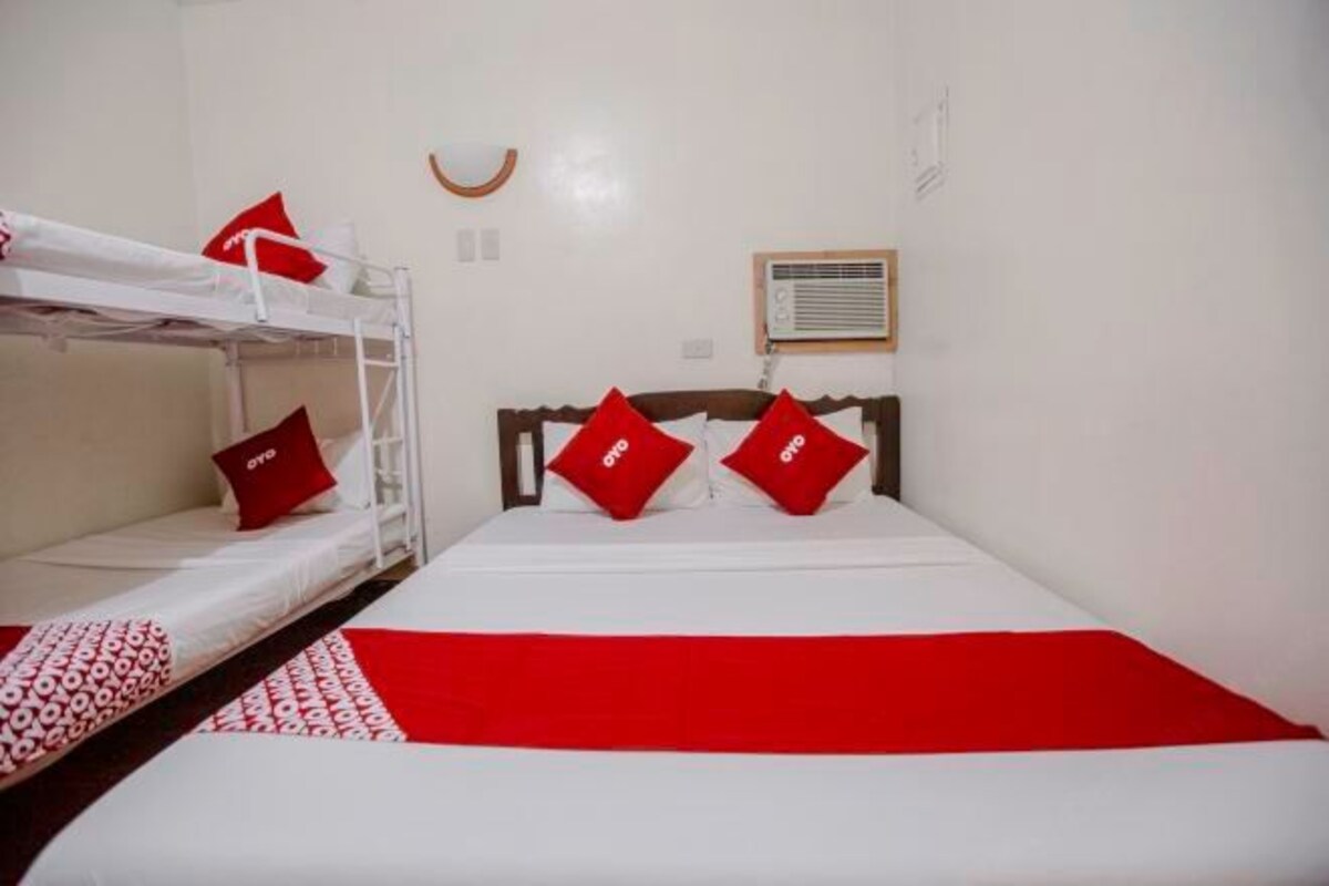 A room with a bunk bed, a single bed with red pillows, and a red and white bedspread.