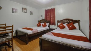A hotel room with two single beds, a wooden chair, a small table, and a red curtain.
