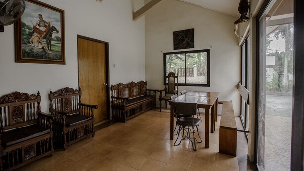 A room with a wooden bench, a dining table with chairs, a large window, and a door.
