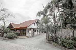 A building with a tiled roof, a gated entrance, and a stone wall. - OYO 741 Sierra Travellers Inns (Tagaytay)