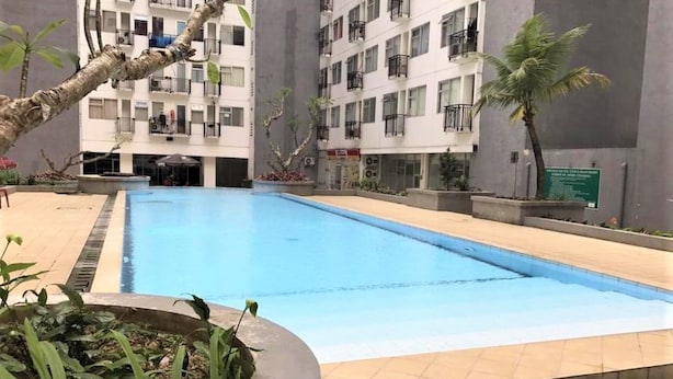 En swimmingpool omgiven av en byggnad med balkonger, en liten trädgårdsyta och en skylt.