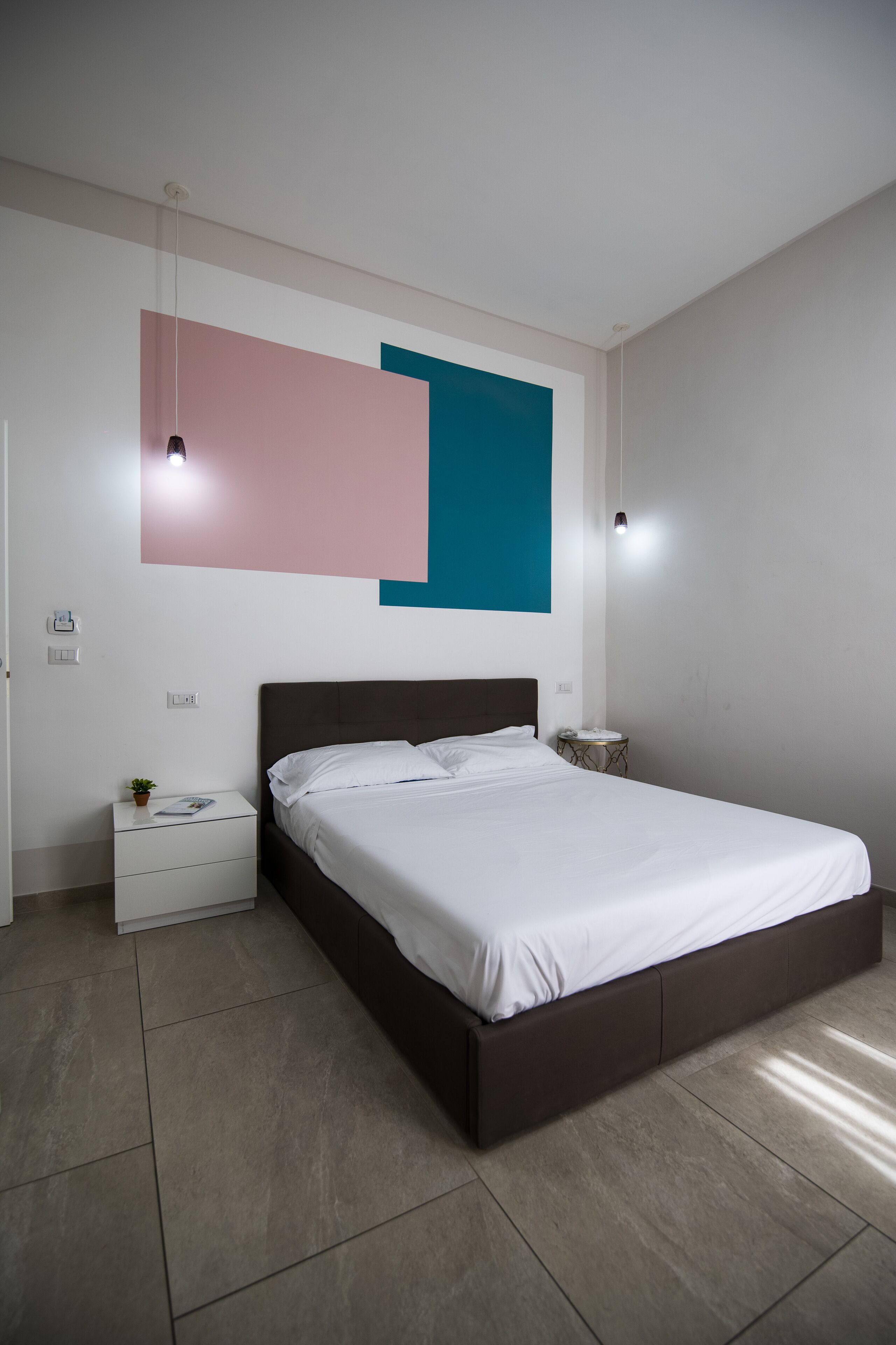 Un dormitorio moderno con una cama grande, una mesita de noche y una lámpara de pared.