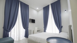 Una habitación de hotel moderna con una cama, un escritorio pequeño y una mesa redonda.