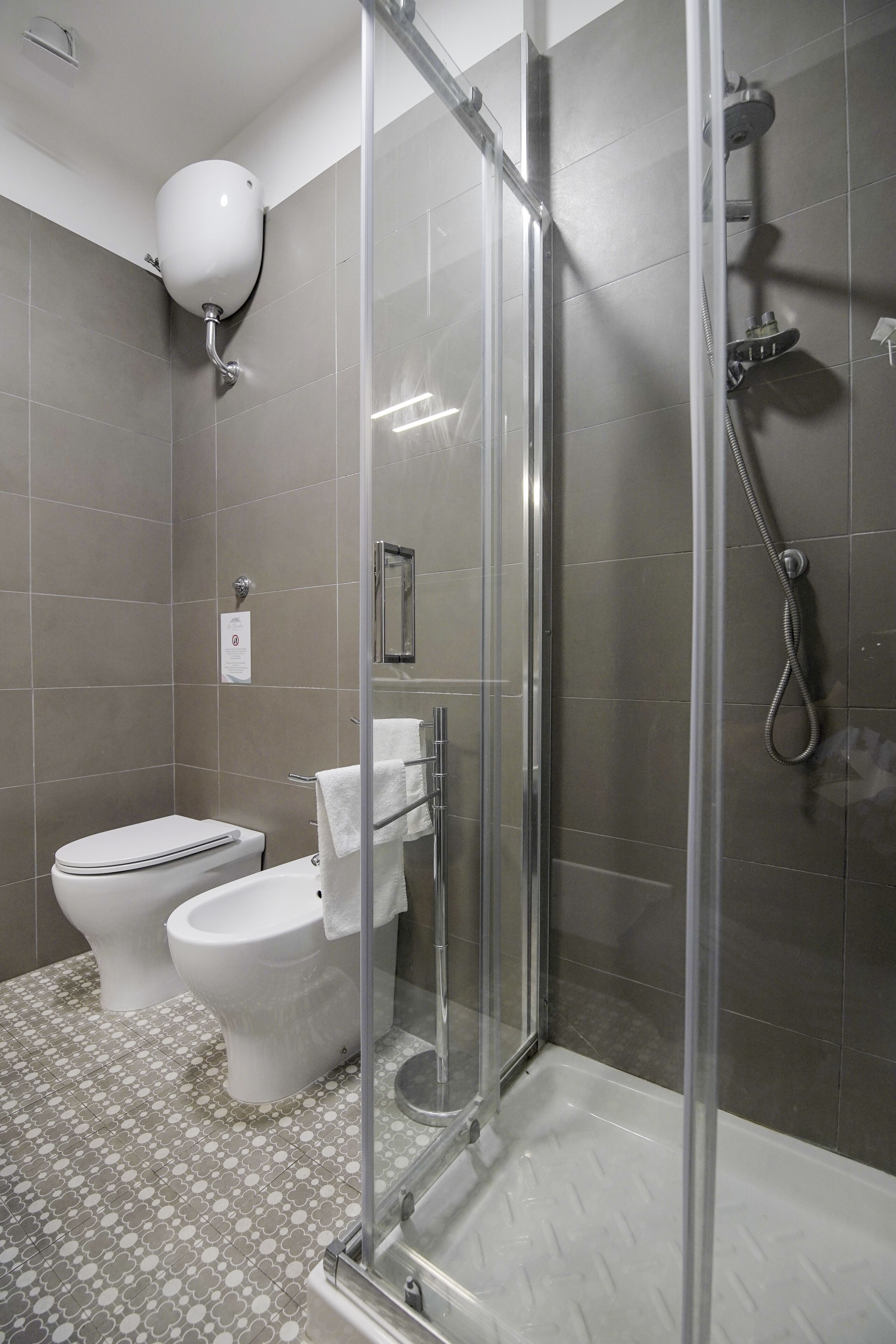 A modern bathroom with a glass-enclosed shower, a toilet, and a bidet.