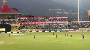 A stadium with multiple tiers of seating, advertisements, and a mountainous backdrop. - Highland Village Resort (Dharamshala)