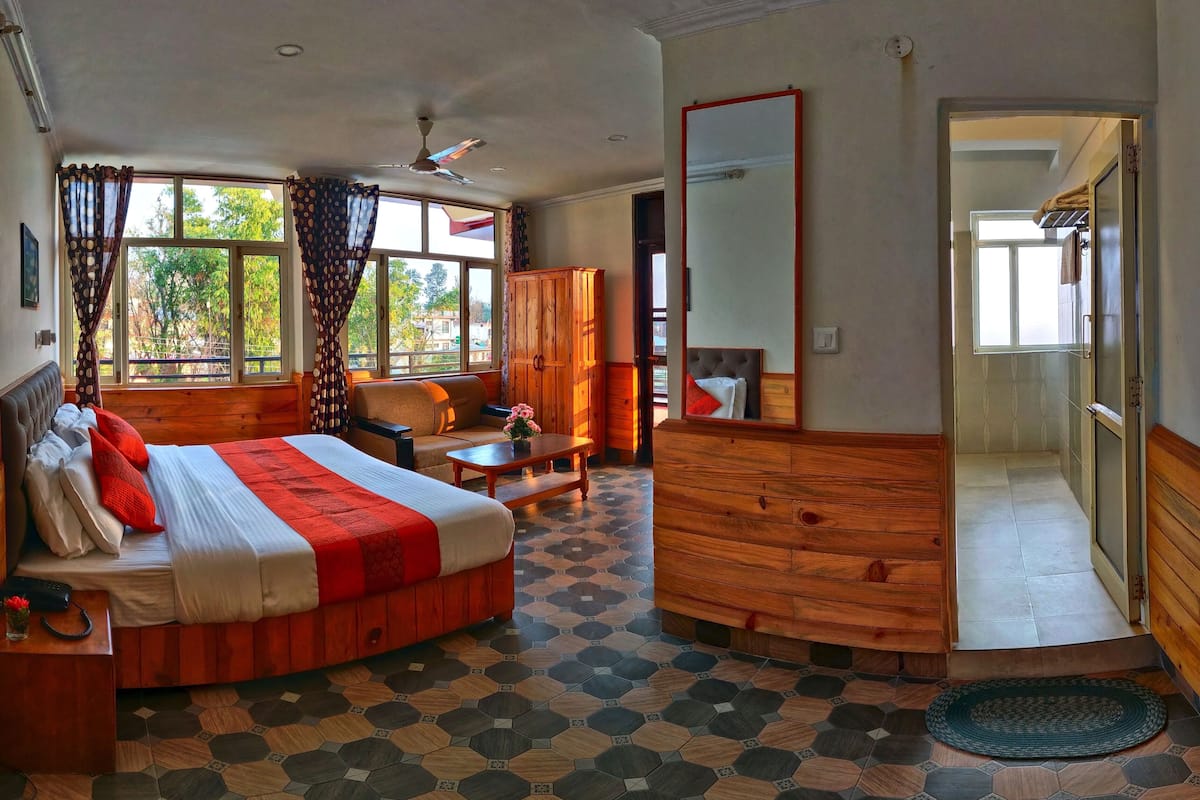 A hotel room with a bed, a desk, a chair, a wardrobe, and a shower area.