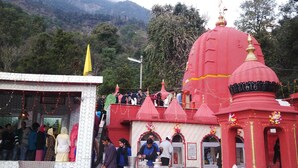 A temple with red domes and a white building with a yellow flag. - Highland Village Resort (Dharamshala)