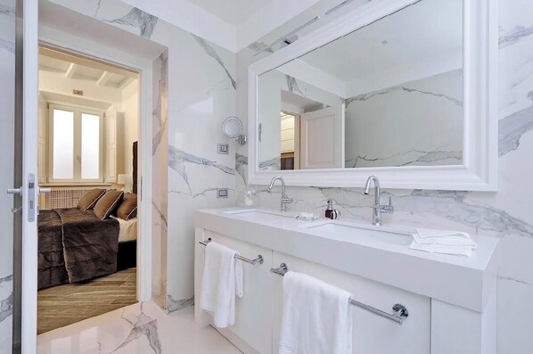 A modern bathroom with a large mirror, white marble backsplash, and a double sink.