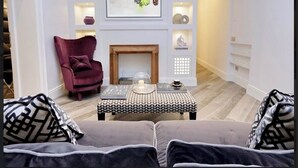 A living room with a fireplace, a red armchair, a patterned ottoman, and a sofa with patterned cushions. - Reale Luxury home  (Roma)