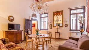 A cozy living room with a round table, chairs, a sofa, and a television. - Fenice Backstage over Canal (Venice)