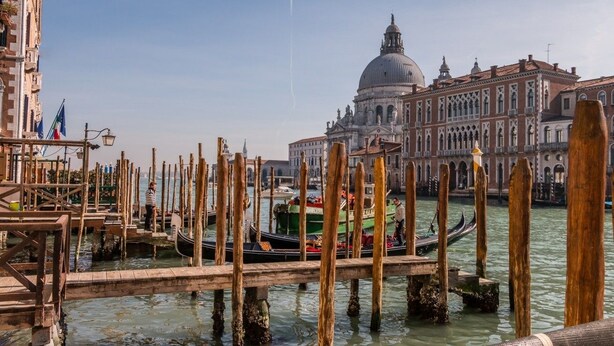 A canal with wooden walkways and gondolas, a large domed building, and a bridge in the background. - Fenice Backstage over Canal (Venice)
