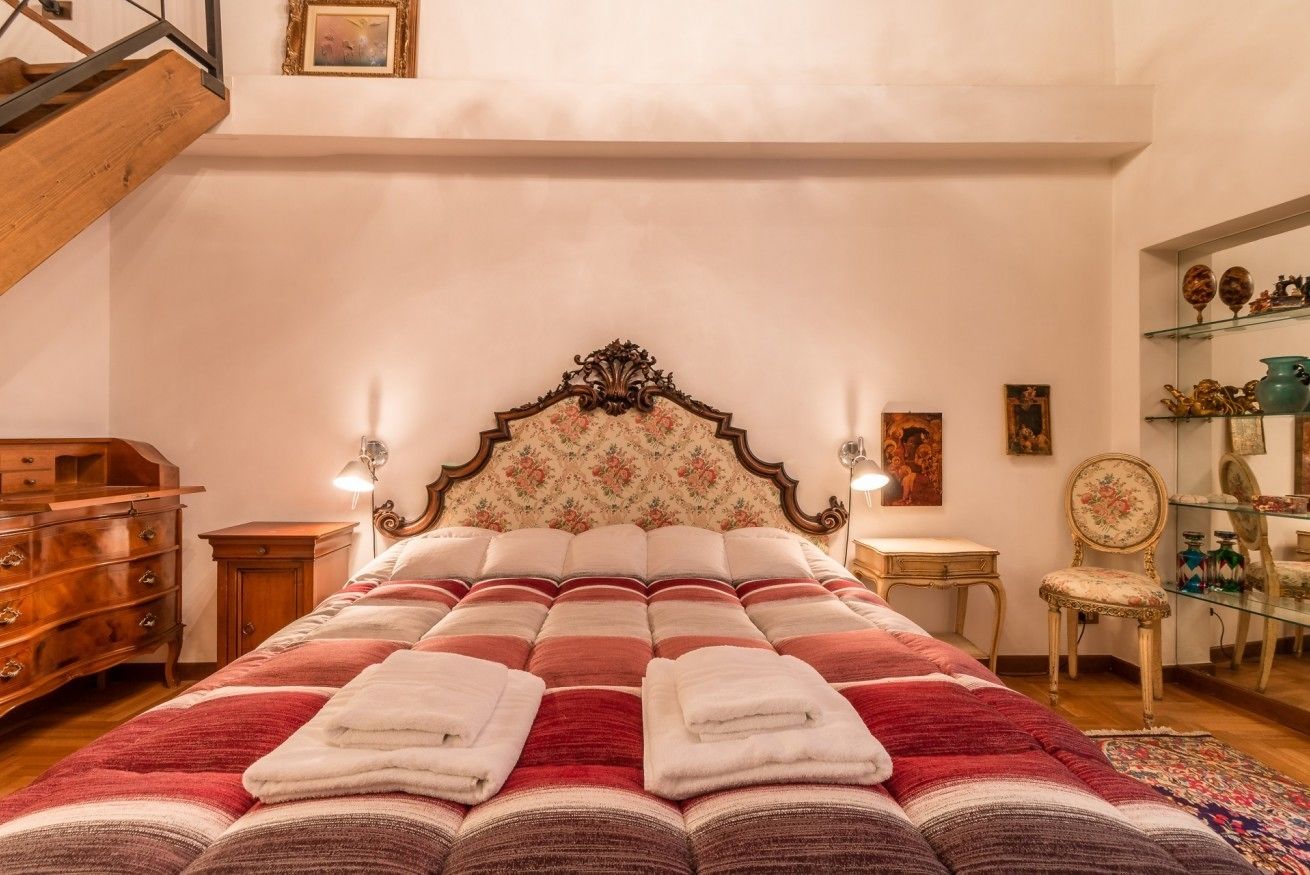 Ein Schlafzimmer mit einem großen Bett, Holzmöbeln, einer Treppe und einer Wandverkleidung.