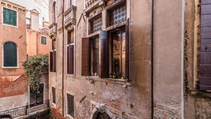A narrow alleyway with buildings featuring arched windows and a small staircase. - Fenice Backstage over Canal (Venice)