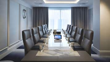 A conference room with a long table, leather chairs, and a large window.
