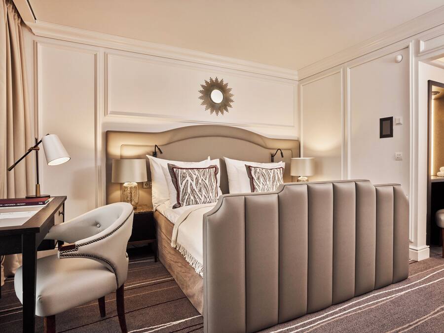 A hotel room with a large bed, bedside tables, a desk, and a chair.