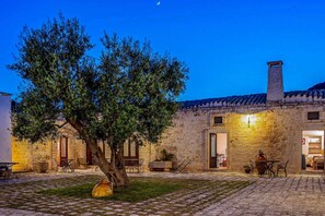 A stone building with a courtyard, a tree, and outdoor seating.