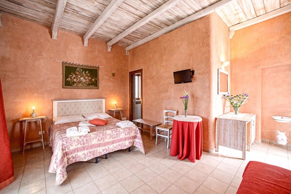 A bedroom with a bed, bedside tables, a small round table with a vase, a chair, and a wooden cabinet.
