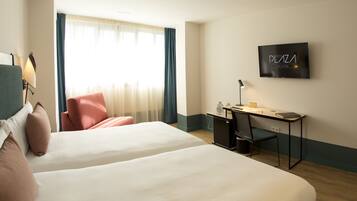 A hotel room with two beds, a desk, a chair, a TV, and a window with curtains.
