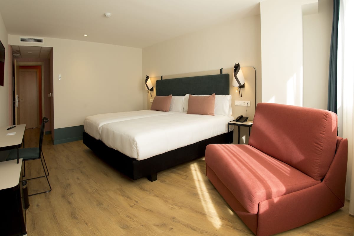 Une chambre d’hôtel avec un lit, un bureau, une chaise et un canapé.