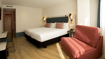 Ein Hotelzimmer mit Bett, Schreibtisch, Stuhl und einer Couch.