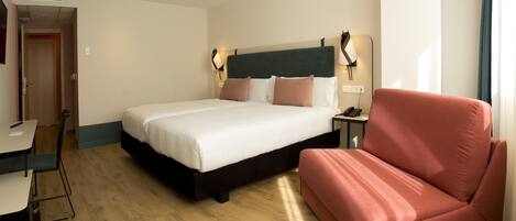 A hotel room with a bed, a desk, a chair, and a sofa.