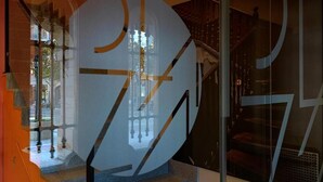 Ein modernes Interieur mit einer großen, abstrakten Skulptur, einer Treppe und einem Glastrennwand.