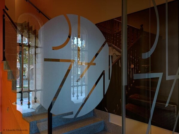 Un intérieur moderne agrémenté d’une grande sculpture abstraite, d’un escalier et d’une cloison en verre.