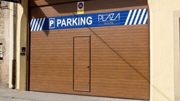 A closed garage door with a 'PARKING' sign and a 'Hotel Plaza de la Paz' sign above it.