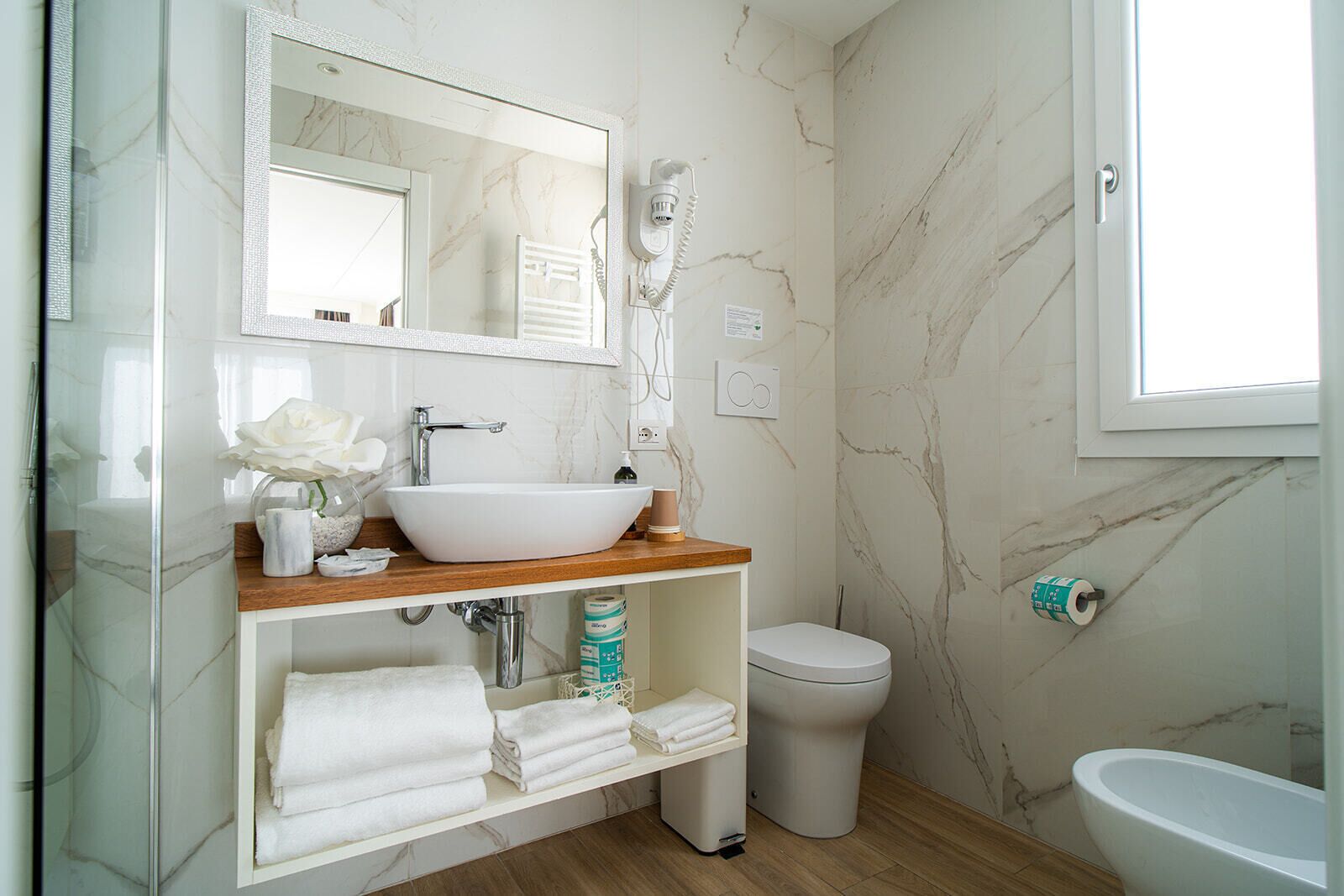 Un baño con lavamanos, espejo y retrete blancos.