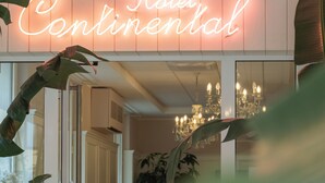 A hotel interior with a neon sign reading "Hotel Continental," a chandelier, and indoor plants. - Hotel Continental (Pietra Ligure)