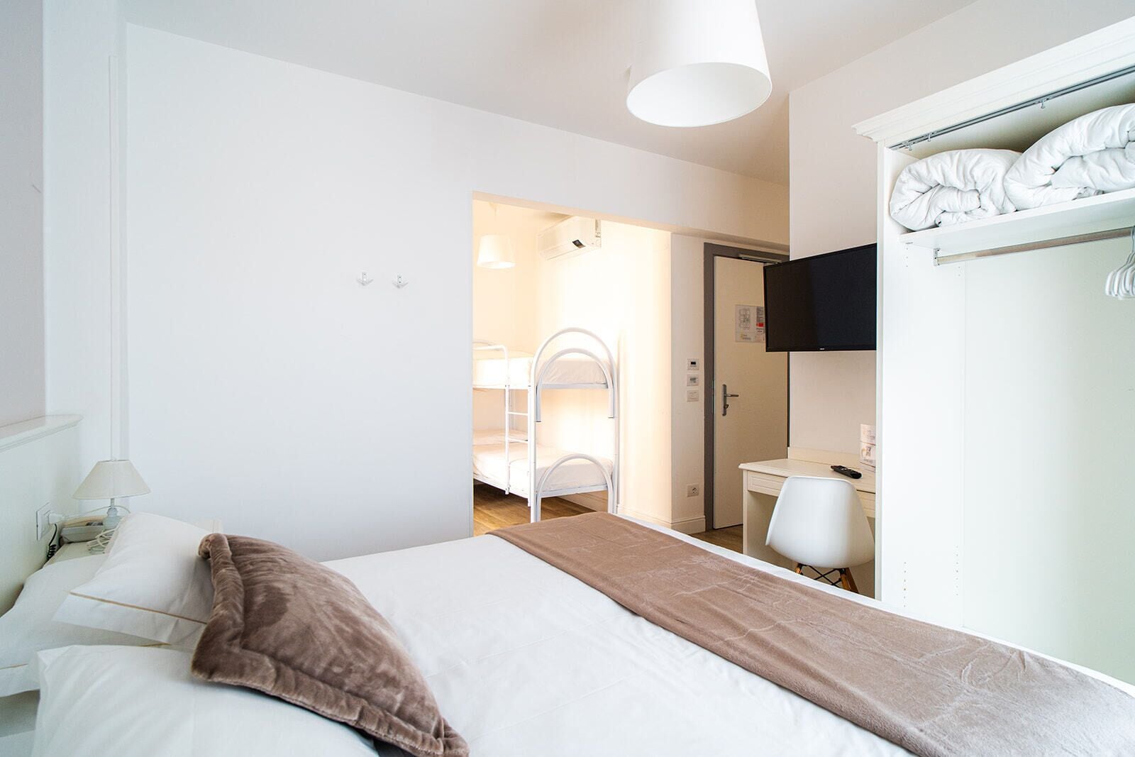 Ein Hotelzimmer mit Bett, Schreibtisch, Stuhl, Kleiderschrank und Fernseher.