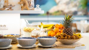 A table with bowls of food, a pineapple, and a basket of kiwis. - Hotel Continental (Pietra Ligure)