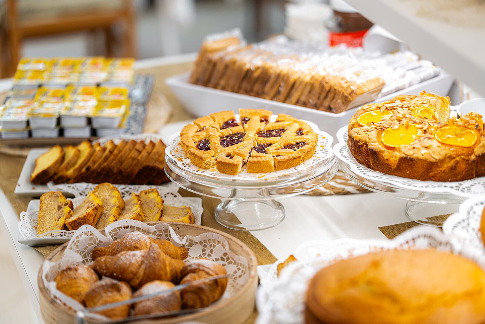 Una variedad de productos horneados expuestos en una mesa, incluyendo tartas, pan y pasteles.