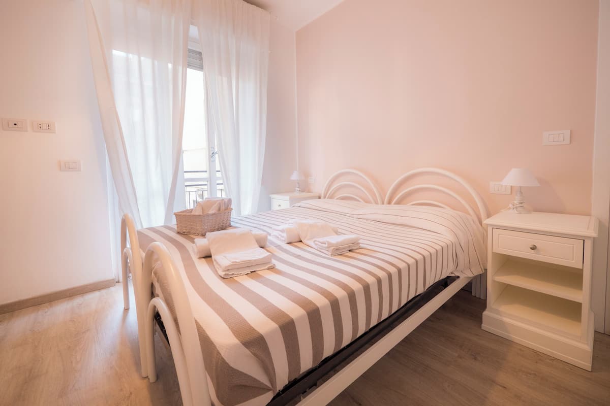 A neatly arranged bedroom with a bed, bedside tables, and a window with curtains.