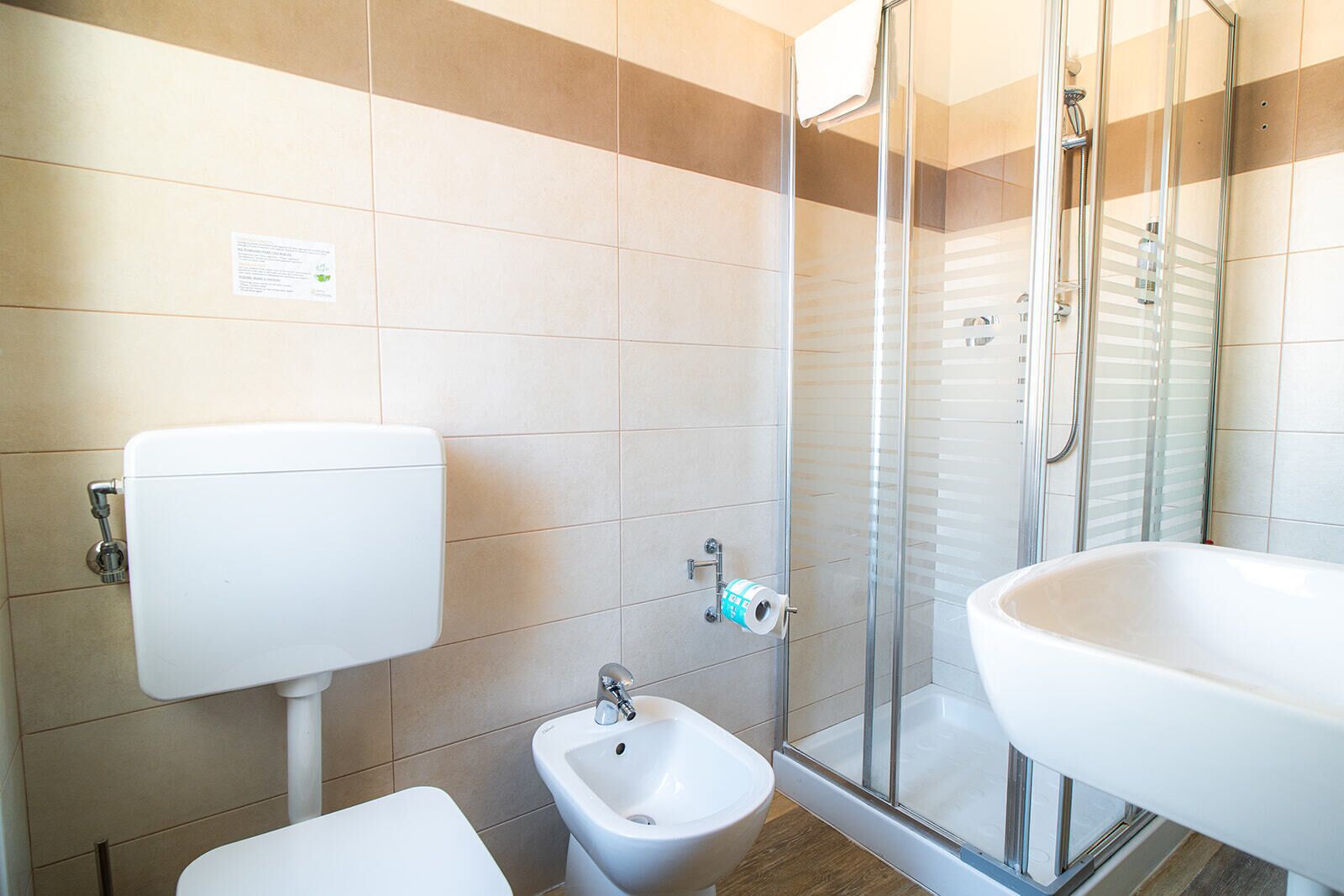 A bathroom with a toilet, bidet, shower, and sink.