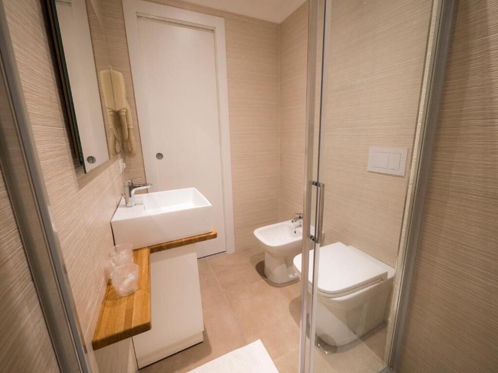 Un bagno moderno con box doccia in vetro, lavandino bianco e water.