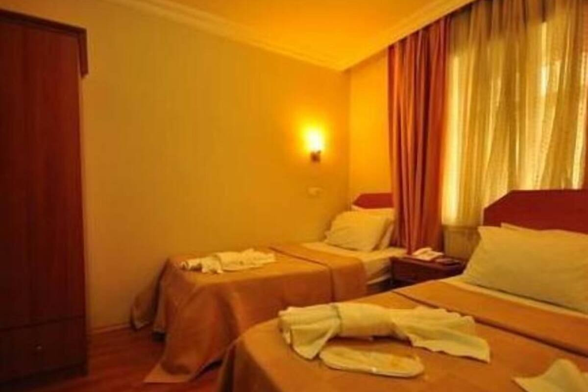 A hotel room with two beds, a nightstand, a lamp, and a wardrobe.