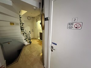 Un couloir d’hôtel avec un comptoir de réception, une horloge et une porte sur laquelle est apposée une pancarte indiquant « Ne pas frapper ».