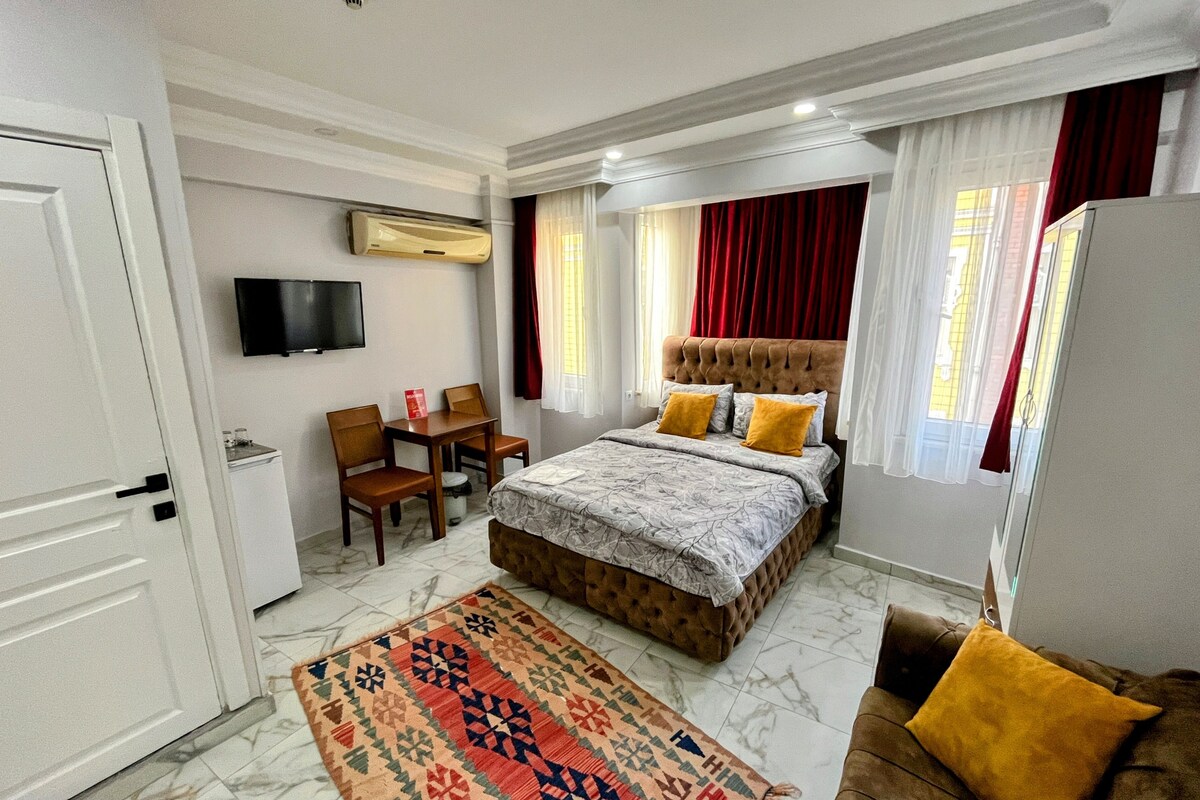 A hotel room with a bed, a TV, a desk, and a chair.