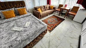 A hotel room with a bed, a sofa, a dining table, and a refrigerator. - Pembe Hotel (Istanbul)