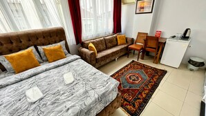 A hotel room with a bed, two sofas, a small desk, and a refrigerator. - Pembe Hotel (Istanbul)
