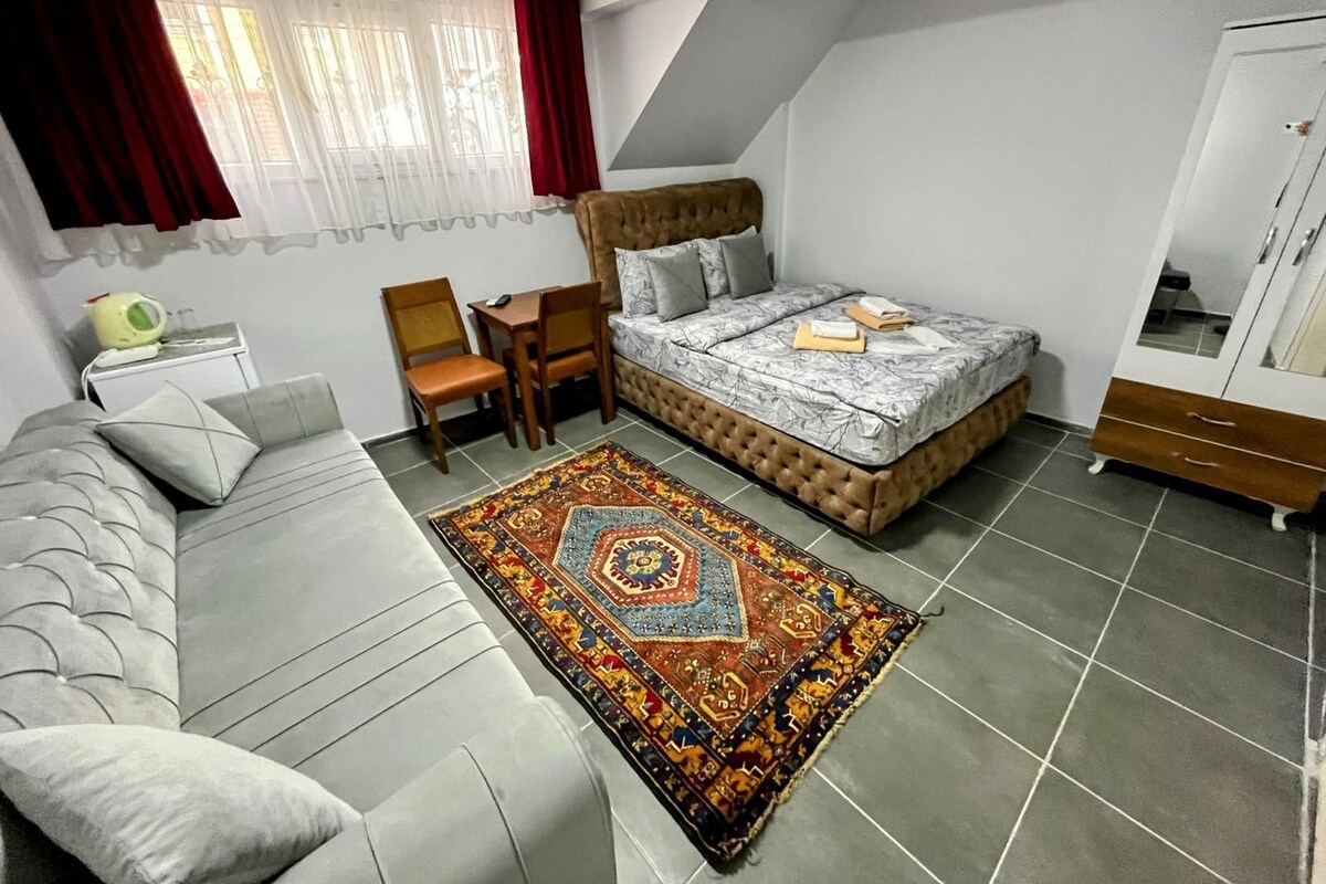 A bedroom with a bed, a sofa, a chair, a small table, and a wardrobe.