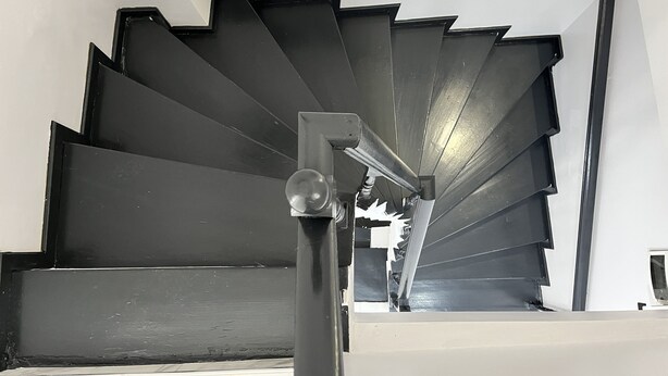 A spiral staircase with a modern design, featuring a black railing and a central column with a light fixture. - Pembe Hotel (Istanbul)