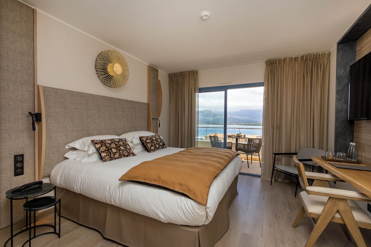 Una habitación de hotel moderna con una cama grande, un escritorio y vistas al mar.