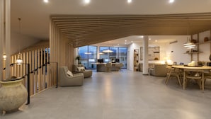 Un vaste espace de vie au design moderne, comprenant une grande table à manger, des sièges confortables et une vue dégagée grâce à de grandes fenêtres.