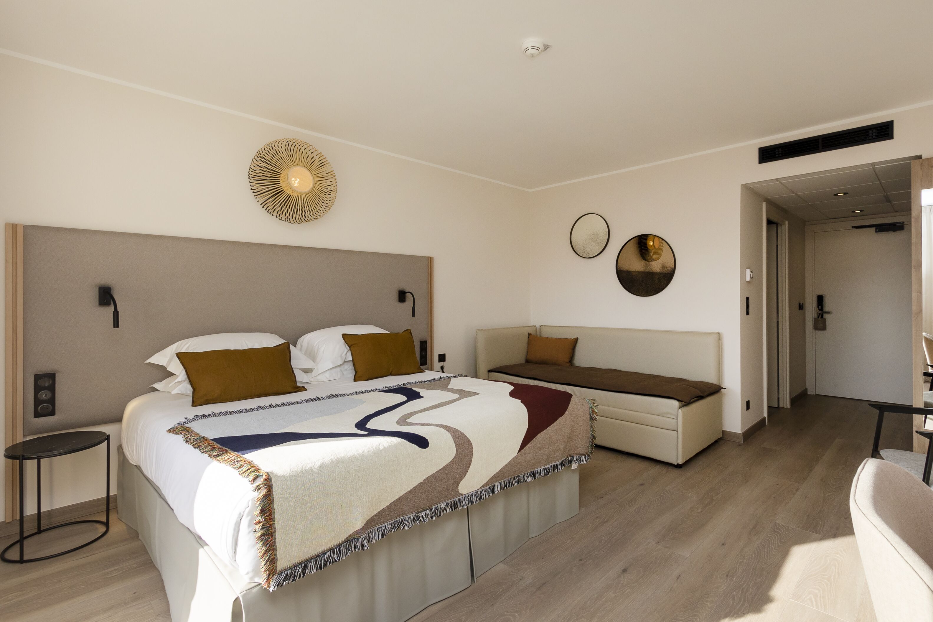 A modern bedroom with a large bed, a sofa, and a small table.