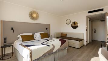 A modern bedroom with a large bed, a sofa, and a small table.