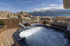 A hot tub on a wooden deck with a cityscape and mountains in the background. - L'Acquale (Calvi)