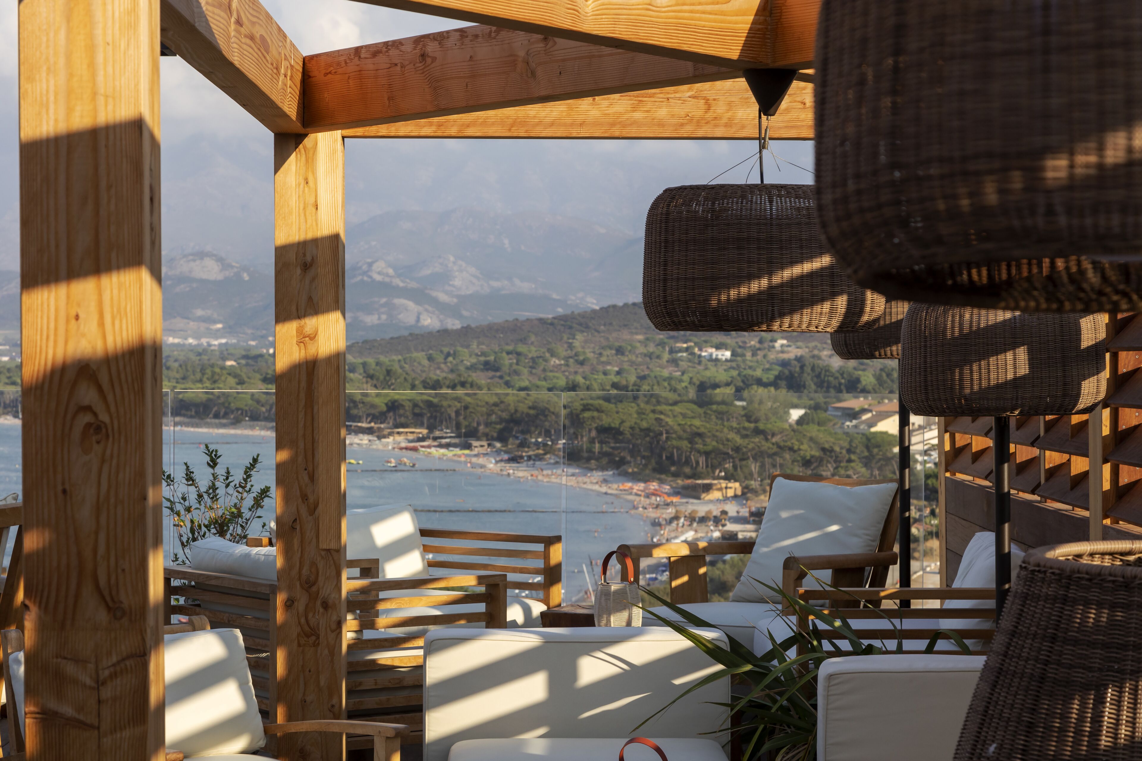 Terraza de madera con mobiliario de mimbre y vista al mar.